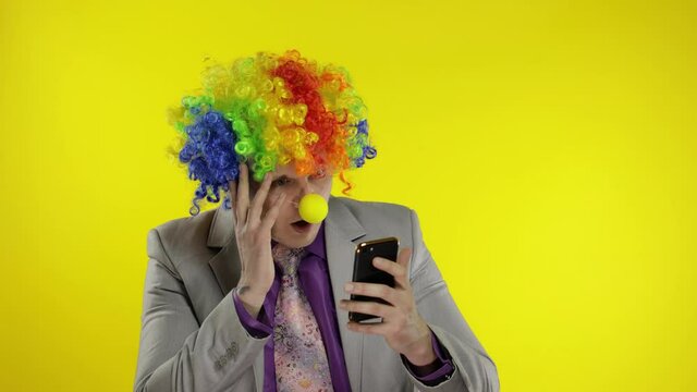 Clown businessman entrepreneur boss in wig losing at work, grabs head. Problems
