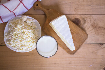 Tasty fresh milk on a white wooden background. glass of milk, cheese on the board and cottage cheese. view from above. copy space