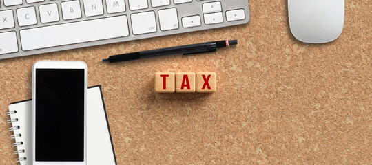 cubes with the word TAX and computer keyboard, smartphone and notepad on cork background