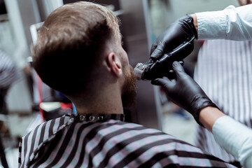 Naklejka premium Foto detalle de maquina de barbero cortando barba a cliente en barbería profesional