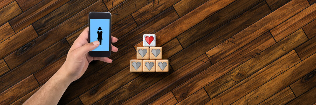 hand with smartphone and cubes with heart icons on wooden background