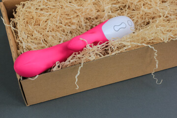 Sex toy for adult, design pink dildo vibrator lying in an open craft box as a gift. Concept of sex,...