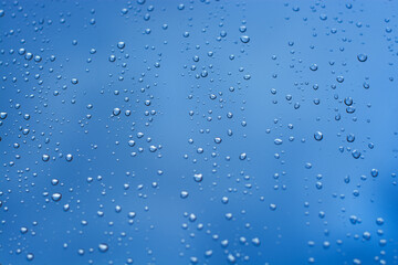 gotas de lluvia sobre vidrio en fondo azul