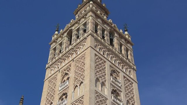 4K. Ultra HD. View of La Giralda Tower with a clear blue sky in the background. Bell tower of the cathedral. The largest cathedral in the world located in Seville, Spain. 