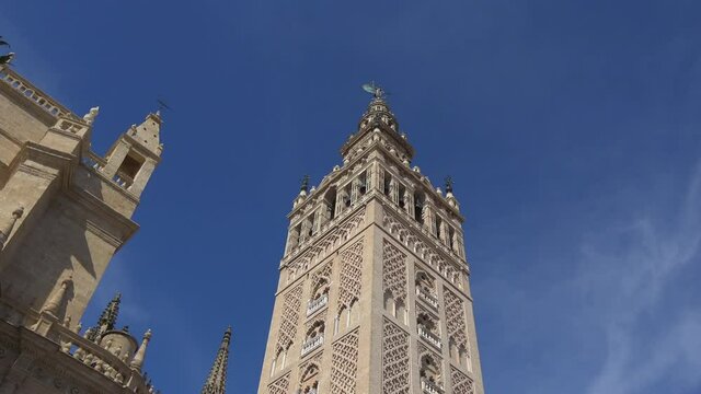 4K. Ultra HD. View of La Giralda Tower with a clear blue sky in the background. Bell tower of the cathedral. The largest cathedral in the world located in Seville, Spain. 