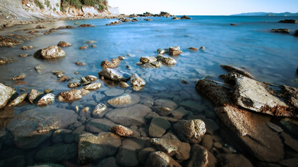 Rocky coast bay of mediterranean sea. Water on long exposure. Sunlight effect. Tourism and vacation, travelling concept. Geographic features banner.