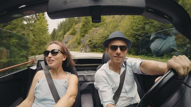 4K Couple riding in convertible wearing sunglasses having ardent conversation. Transportation concept, relationships concept.