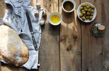 Ciabatta. Fresh italian ciabatta bread with herbs, olive oil and olives on grey background, top view, copy space.