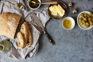 Ciabatta. Fresh italian ciabatta bread with herbs, olive oil and olives on grey background, top...