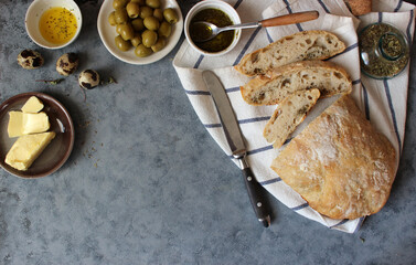 Ciabatta. Fresh italian ciabatta bread with herbs, olive oil and olives on grey background, top...