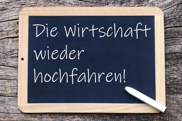 Fototapeta premium Schreibtafel mit der Schrift: Die Wirtschaft wieder hochfahren!