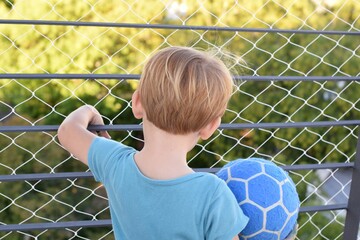 Two years old blond boy playing at the terrace during quarantine for coronavirus. There is a security net on the balcony. 21st March, 2020, Buenos Aires, Argentina.