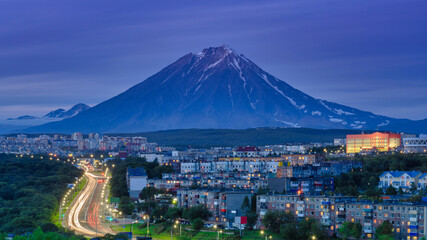 Panorama of night city of Petropavlovsk-Kamchatsky on background cone of volcano, urban development...