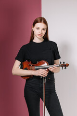 Girl in black plays violin on pink background