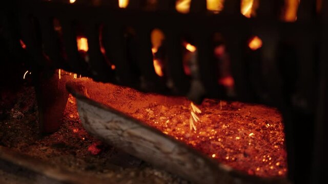 Opening door of stove and stoking coals embers falling
