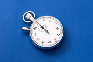 Analogue metal stopwatch on the blue background.