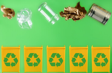 Throwing paper, metal, glass, plastic, organic garbage into different yellow containers on a light green background. Waste separation and recycling concept.