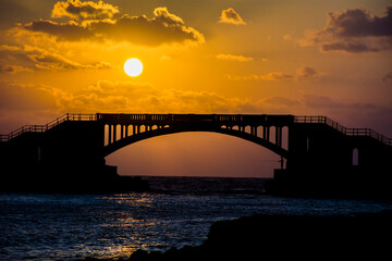 sunset over the bridge at Alexandria and there is a fisherman who fish under the bridge 