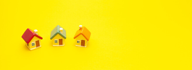 Miniature colored houses on a yellow background, space for text