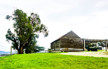 Fototapeta na wymiar Historic old hay barn farm shed on country farm with large tree