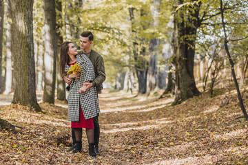 Young family having fun among yellow trees and leaves.