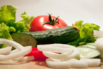 tomato cucumbers onions and lettuce closeup on a white background