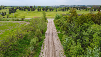 Fototapeta na wymiar Aerial View of Countryside with Trail surrounded by green trees and grass during blue sky weather
