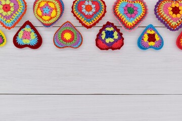 Knitted hearts are placed on white wooden boards.