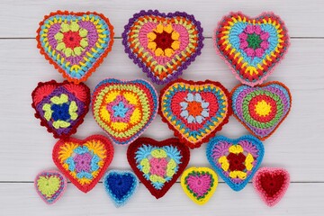 Knitted hearts are placed on white wooden boards.