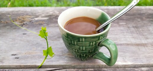 Morning coffee and nature on an old wooden table, background of green fields in Thailand.