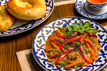 Traditional oriental meat dish with vegetables in painted plates on a plate on a table in a restaurant