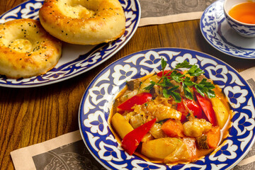 Traditional oriental meat dish with vegetables in painted plates on a plate on a table in a restaurant
