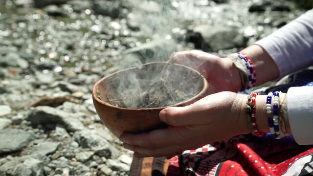 Closeup of a woman Sangoma shaman lowering a burning bowl, honoring her ancestors, slow motion