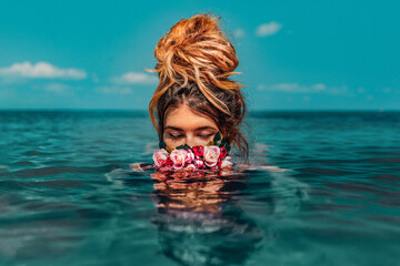 beautiful young woman swimming in sea with wreath conceptual fashion portrait