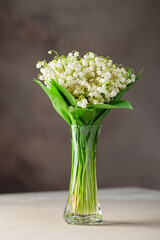 Bouquet flowers lily of the valley in the vase. Spring card.