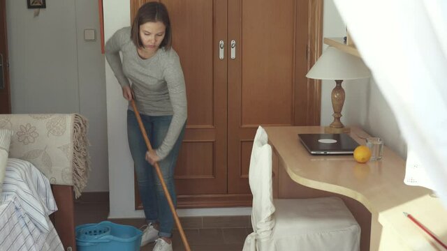 Woman mopping floor in bedroom