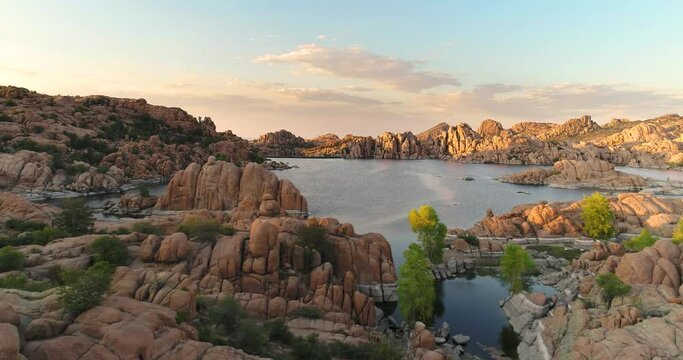 Low angle aerial view of lake above exotic granite rock formations in Prescott, Arizona near sunset with beautiful warm colors and rich skies.