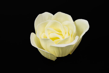 bud blossoming beige rose, soap rose, body soap lies on a black background.
