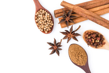 Closeup Cinnamon sticks, star anice or badiane and coriander seeds, cardamon or sichuan pepper in wooden spoon isolated on white  background. Natural herbal plant,spices seasoning concept.Top view 