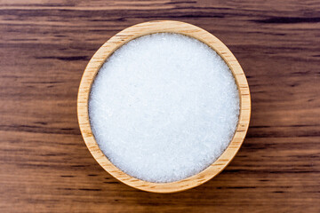 Close-up Monosodium glutamate ( MSG ) in wooden bowl isolated on rustic wooden table background. Top view. Flat lay.