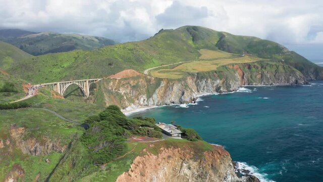 Breathtaking distant view over the famous beautiful landmark, Bixby Bridge. The arch bridge on the Big Sur coast of California. Lots of cars are seen on the view point and on the way to the bridge. 4k