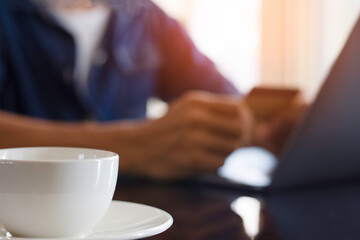 Blurred image of casual man hand make online payment, pay bill and internet banking by using debit or credit card and laptop computer. e business, internet banking concept. Flare light.
