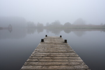 wooden pier at lake on misty autumn day