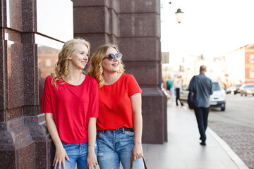 Young girls tourists on street walk. Street style portrait. Beautiful women friends in city. Stylish females on stairs weared in red casual outfit. Life style. Summer. Local tourism. Summer Kiev City