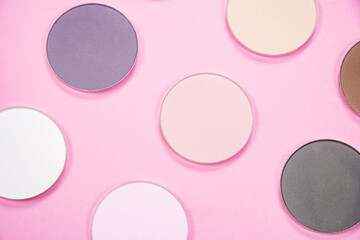 Pattern of eye shadows of different colors on a pink background