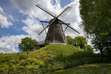 Obraz premium Old windmill on a hill with blue sky and clouds