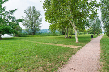 Dirt path in the park by the lake. Lake Varese and the green area of Schiranna or Zanzi park, northern Italy. Lake famous because hosts rowing competitions of national, European and world level