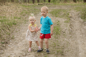 Fototapeta premium Brother and sister walk along the forest road