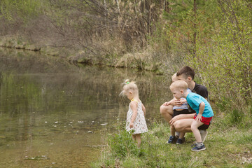 Children on a river in a forest catch fish