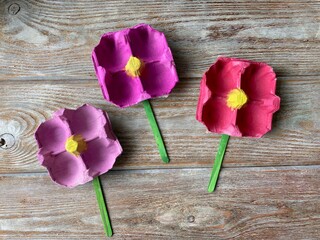 Three pink flowers children's crafts on a wooden background